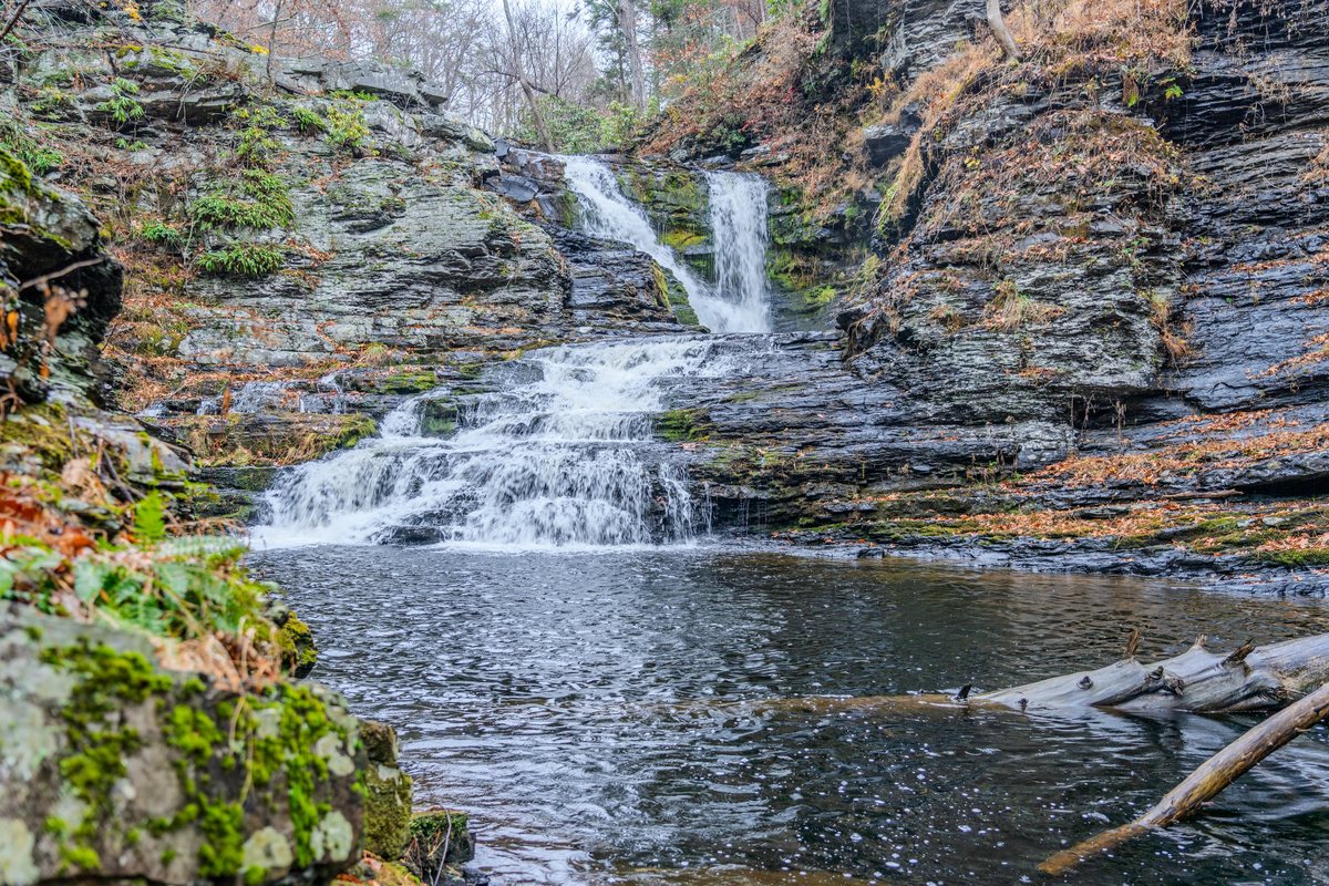 Wide view of the natural waterfall and plunge pool in the Poconos forest.