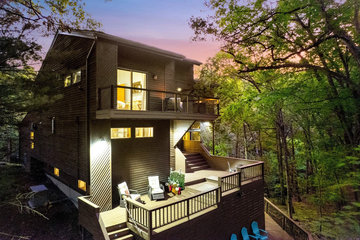 Exterior decks at Waterfall Wonder glowing at dusk in the Poconos forest.